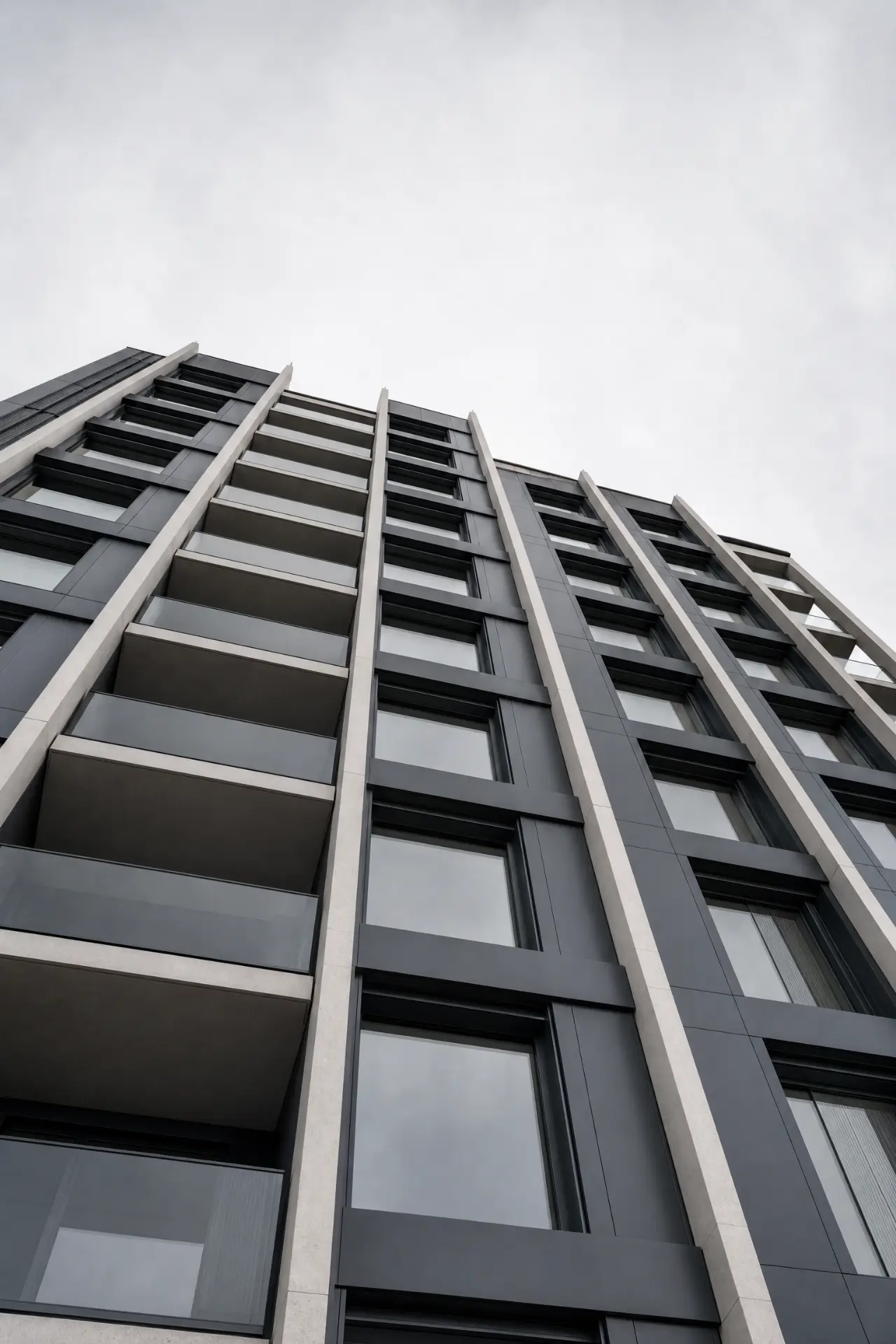 High-rise façade viewed from below with repeating stone and dark metal bays